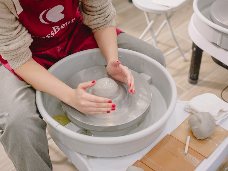 Hands shaping clay on a throwing wheel in a pottery class
